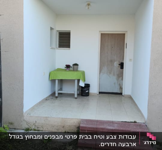 דלת עץ עם סימני צבע, קיר לבן, שולחן עם מפה ירוקה